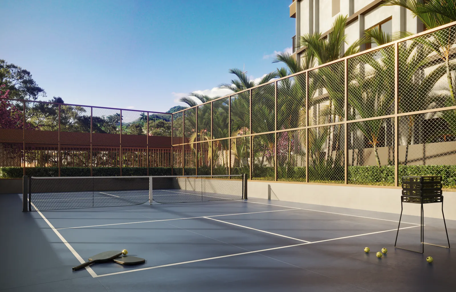 Quadra de pickleball com rede e cerca, com o verde ao fundo