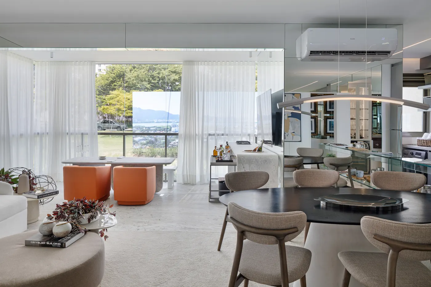 Sala do decorado de 3 suítes, com poltronas laranja e vista para a janela