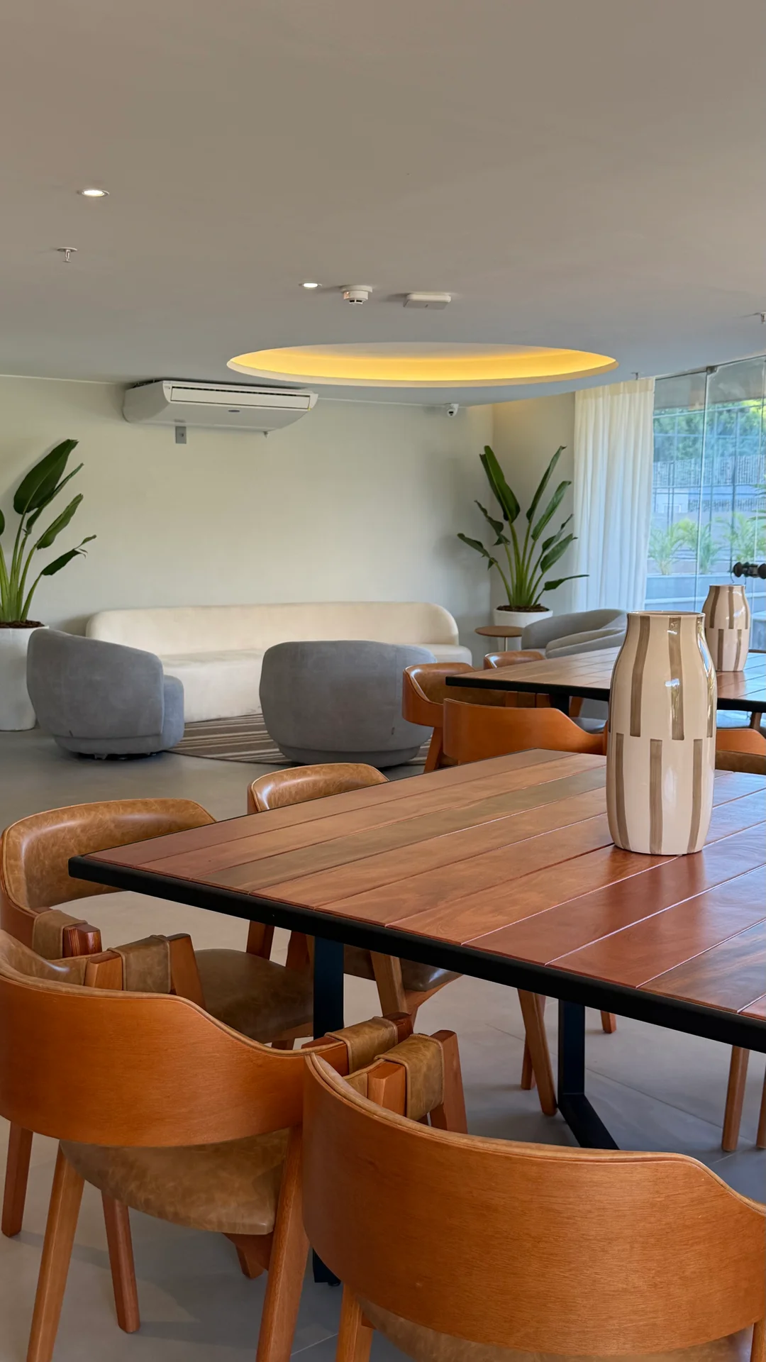Coworking com mesas grandes de madeira e sofá curvo
