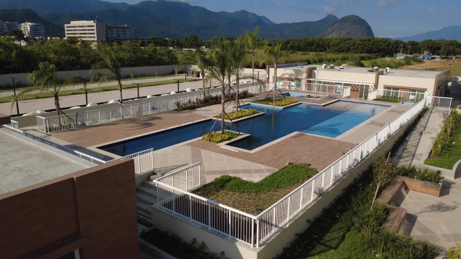 Foto real da piscina do Clube Palms pronta, com deck e as montanhas ao fundo